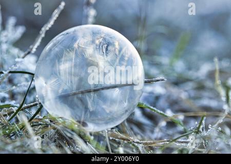 Seifenblase, auf der sich durch den Frost Eiskristalle gebildet haben. Im Licht der untergehenden Sonne. Auf der Seifenblase Due werden filigrane Muster erstellt Stockfoto