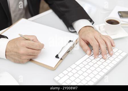 Männliche Hände mit modernen Computer und Schreiben mit Kugelschreiber Business Konzept Stockfoto