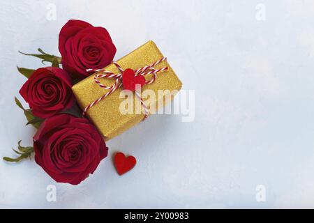 Rote Rosen und goldenen Geschenkkarton mit Band auf blauem Hintergrund Raum bewältigen Stockfoto