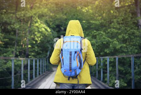 Tourist-Mann zu Fuß über Holzbrücke über Bergfluss Stockfoto