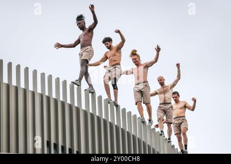 London, Großbritannien. 31. August 2024. Fünf Parkour-Künstler der Compagnie Lézards Bleus machen eine Reise durch die architektonischen Landschaften und Gebäude der Greenwich-Halbinsel, wobei ein großes Publikum jede Bewegung beobachtet. Im Laufe ihrer Reise verstörte Lézards Bleus die Erwartungen und schuf eine Reihe sich entwickelnder Bilder, die unsere Vision des öffentlichen Raums verändern. Die Aufführung ist Teil des Greenwich Docklands International Festival (GDIF) Credit: Imageplotter/Alamy Live News Stockfoto