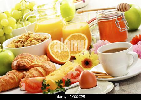 Das Frühstück, bestehend aus Obst, Orangensaft, Kaffee, Honig, Brot und Ei. Ausgewogene Ernährung Stockfoto