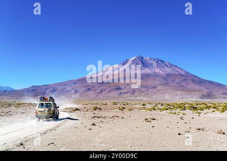 Blick auf den schlafenden Vulkan Tunupa am Rande des Uyuni Salzsee in Bolivien mit dem Transport Stockfoto