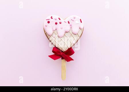 Schmelzendes Eis-Herz-Lebkuchen-Keks. Valentinskarte. Rosafarbener Hintergrund. Stockfoto