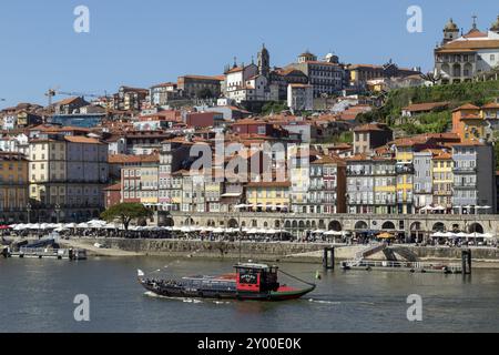 Ausflugsboot auf dem Fluss Douro und historische Fassaden von Geschäften und Restaurants an der Promenade Cais da Ribeira im historischen Zentrum von Porto, Hafen Stockfoto