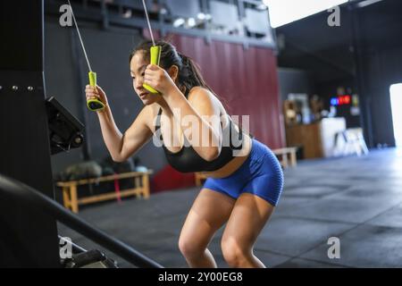 Chinesin mit Latmaschine Gewichte in einem Crosstraining-modernen Fitnessstudio Stockfoto