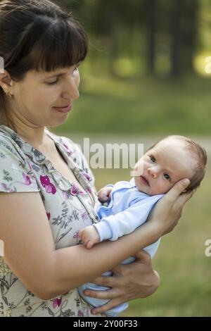 Liebevolle Mutter Hand hält süßes kleines neugeborenes Baby Kind, das im Freien läuft Stockfoto