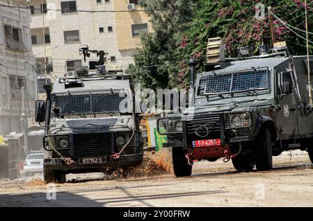 Jenin, Palästina. 31. August 2024. Israelische gepanzerte Fahrzeuge fahren während eines Armeeangriffs in Jenin auf einer Straße. Die israelische Armee sagte, zwei Palästinenser seien über Nacht getötet worden, als sie sich auf die Bombenangriffe im besetzten Westjordanland vorbereiteten, wo am vierten Tag eine israelische Operation begann. Quelle: SOPA Images Limited/Alamy Live News Stockfoto