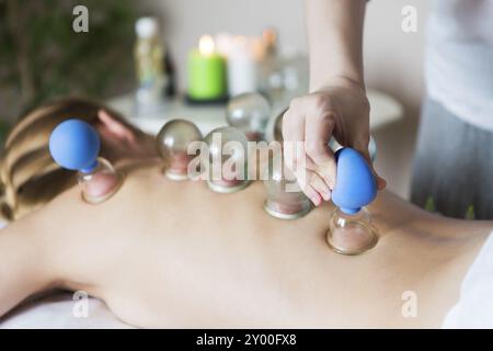 Junge Frau eine Behandlung an der Medizinischen Klinik. Feuer schröpfen Cups auf der Rückseite des weiblichen Patienten in der Akupunktur Therapie Stockfoto