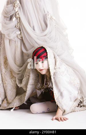 Das kleine Mädchen spielt Verstecken in einem Piratenkostüm Stockfoto