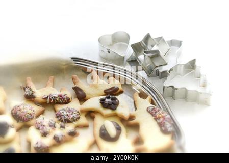 Frisch gebackene Weihnachtsgebäck auf einem antiken silbernen Tablett und Keksschneider im Hintergrund. Frisch gebackene Weihnachtsplätzchen, farbenfroh dekoriert Stockfoto