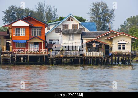 Eine Reihe von Wohnhäusern steht auf Stelzen über dem Fluss Chao Phraya in Bangkok, Thailand, Asien Stockfoto