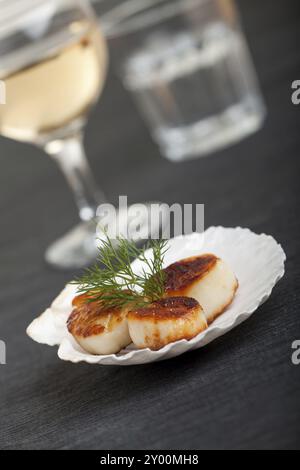 Gegrillte Jakobsmuscheln mit Schale auf einem schwarzen Plazemat Stockfoto