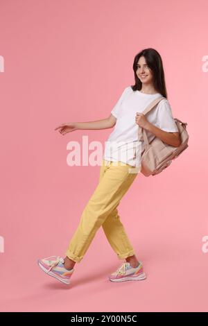 Fröhliches Mädchen im Teenageralter mit Rucksack auf rosa Hintergrund Stockfoto