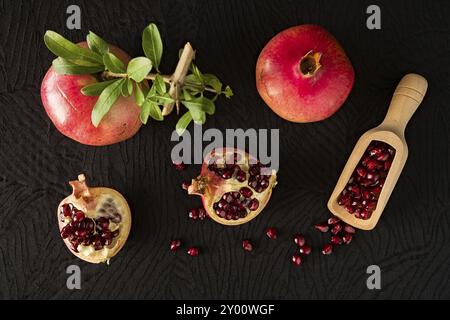 Reifer Granatapfel Obst und bailer mit Samen im Inneren von oben über einem schwarzen strukturierten Hintergrund gesehen Stockfoto