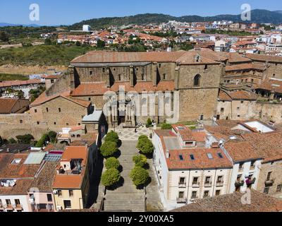 Große historische Kirche mit breiten Stufen und umgeben von alten Gebäuden mit roten Dächern in einer hügeligen Landschaft, aus der Vogelperspektive, Plasencia, Caceres, Caceres, E Stockfoto