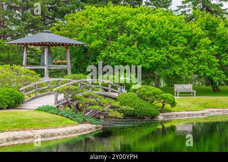 Eine Brücke über ein Wasserspiel vor einer großen Bronzeglocke im Japanischen Garten Nikka Yuko Stockfoto