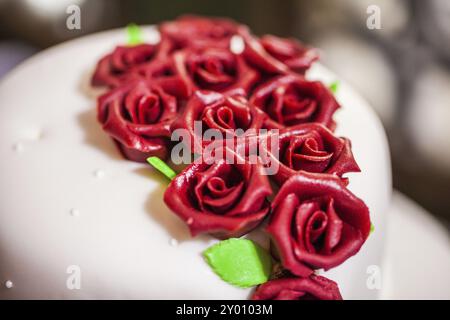 Weiße Hochzeitstorte mit roten Marzipanrosen Stockfoto