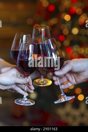 Klirrende Gläser Wein in den Händen auf hellem Weihnachtsbaum Lichter Hintergrund. Veranstaltungsfeier Stockfoto