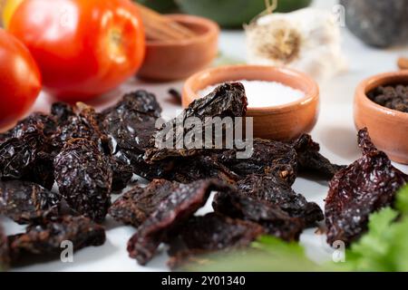 Eine Nahaufnahme eines Haufens getrockneter chiles morita, neben anderen Salsa-Zutaten. Stockfoto