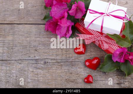 Geschenkboxen, rosa Bougainvillea, drei Herzen auf Holzbrett Stockfoto