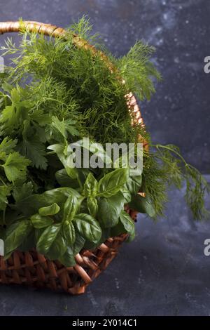 Mischung aus frisch gepflückten Kräutern in Weidenkorb auf rustikalen dunklen Hintergrund Stockfoto