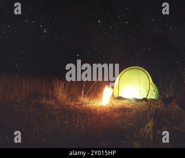 Grüne camping Zelt mit Lagerfeuer im Wald bei Nacht unter den Sternen Stockfoto