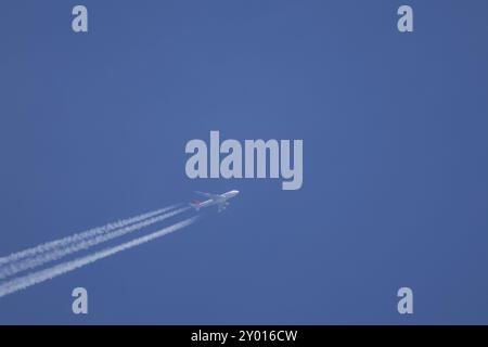 Boeing 747 Jumbo-Jet-Flugzeuge fliegen über einen blauen Himmel mit einer Dampfspur oder einem Kondensstreifen dahinter, England, Großbritannien, Europa Stockfoto