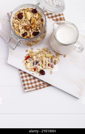 Glas hausgemachtes Müsli mit Nüssen, Beeren, getrockneten Früchten, Milch und Honig auf weißem Hintergrund. Gesundes Frühstück. Draufsicht Stockfoto