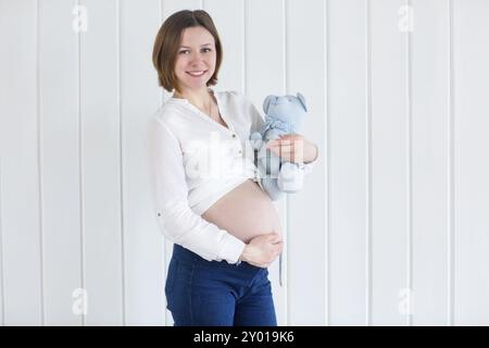 Porträt einer schwangeren Frau hält einen Teddybär Stockfoto