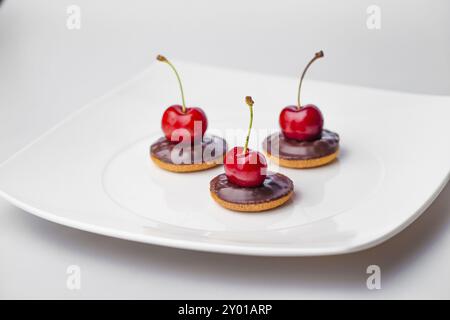 Drei Kirschen auf drei Schokoladenkeksen Stockfoto