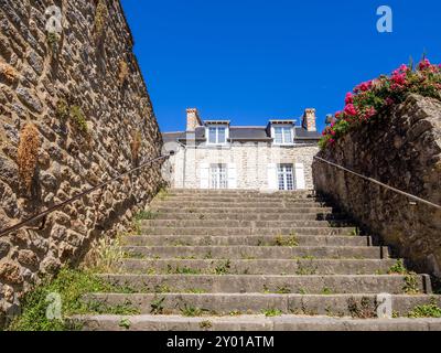 Steintreppen in Dinan, Bretagne, führen zum bezaubernden bretonischen Steinhaus unter sonnigem blauen Himmel. Stockfoto