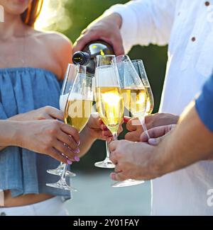 Glückliche Freunde Gießen Champagner Sekt Wein in die Gläser im Freien an einem Strand. Sunset Beach-party Stockfoto