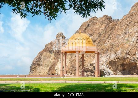 Goldener, verzierter Kuppelpavillon im traditionellen omanischen Stil mit Felsen im Hintergrund, Muttrah, Muskat, Oman Stockfoto