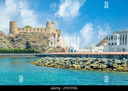 Blick auf die arabische Al Jalali Burg auf den Felsen und weiße königliche Palastgebäude, Muscat, Oman Stockfoto