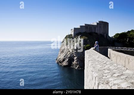 Frau, die von der Stadtmauer aus über das Meer schaut Stockfoto