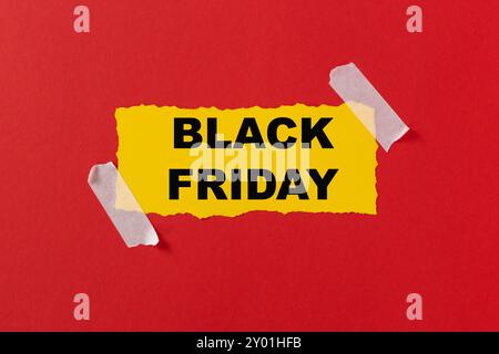 Black friday-Konzept. Draufsicht des gelben Papierbogens und des schwarzen freitagstexts auf rotem Hintergrund. Text im Rahmen. Komposition Black Friday. Lebendig Stockfoto