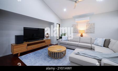 Stilvolles Wohnzimmer mit weichem Sofa und Couchtisch. Innenraum mit hellem Wohnzimmer mit gemütlichen Sofas in der Nähe von großen Fenstern, geräumiges, modernes Wohnzimmer Stockfoto