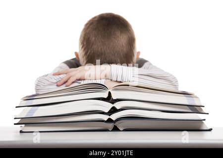 Müder Junge, der in der Ausbildung schläft und Bücher am Schulpult liest Stockfoto