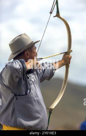 Ulaanbaatar, Mongolei, 11. Juni 2007: Rückansicht eines männlichen Bogenschützen, der eine Bogenschnur zieht, das Ziel anvisiert und Pfeil auf das Naadam Festival schießt Stockfoto