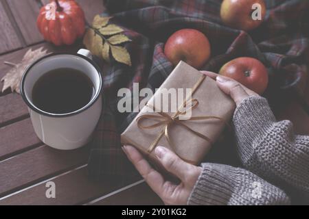 Woman's Hände halten ein Geschenk, trinken heißen Kaffee oder Tee herbst Konzept Stockfoto