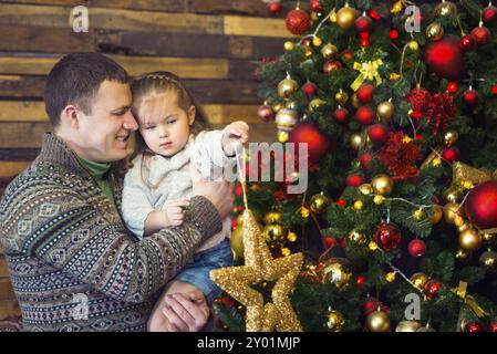 Glücklicher Vater und seiner kleinen Tochter schmücken den Weihnachtsbaum zu Hause Stockfoto