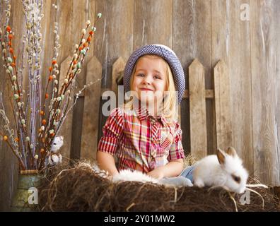 Porträt von eine entzückende kleine Mädchen und kleine weiße Kaninchen in der Nähe von hölzernen Hintergrund. Ostern-Konzept Stockfoto