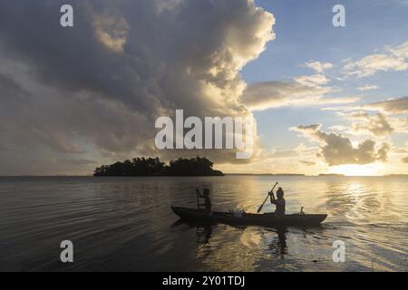 Kinder auf dem Weg zur Schule mit einem Kanu während des Sonnenaufgangs auf den Salomonen Stockfoto