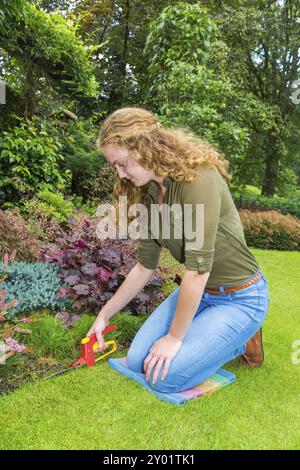 Junge europäische Frau im Garten arbeiten mit grasscheren Stockfoto