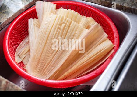 Ein Blick auf einen Haufen Maisschalen in einem Plastiksieb in einer Küchenspüle. Stockfoto