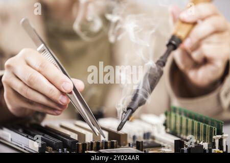 Manuelle Arbeiter menschliche Hand halten Lötkolben Werkzeug Reparatur Computer Elektronikplatine Stockfoto