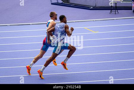 Der blinde französische Paralympic-Athlet Timothée Adolphe mit seinem Reiseleiter lief für die 400-m-Strecke im Stade de France für die Paralympischen Spiele 2024 in Paris. Stockfoto