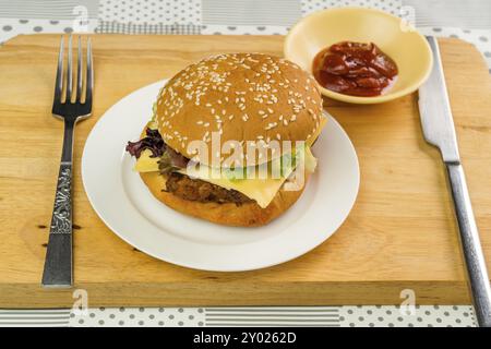 Chicken Burger mit Käse und Gemüse ist bereit, in einer weißen Platte auf Holzbrett zu essen Stockfoto