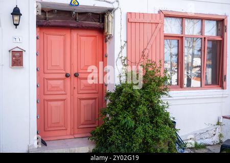 Ein gemütliches Haus im Inselstil mit roten Holzfenstern und Tür Stockfoto